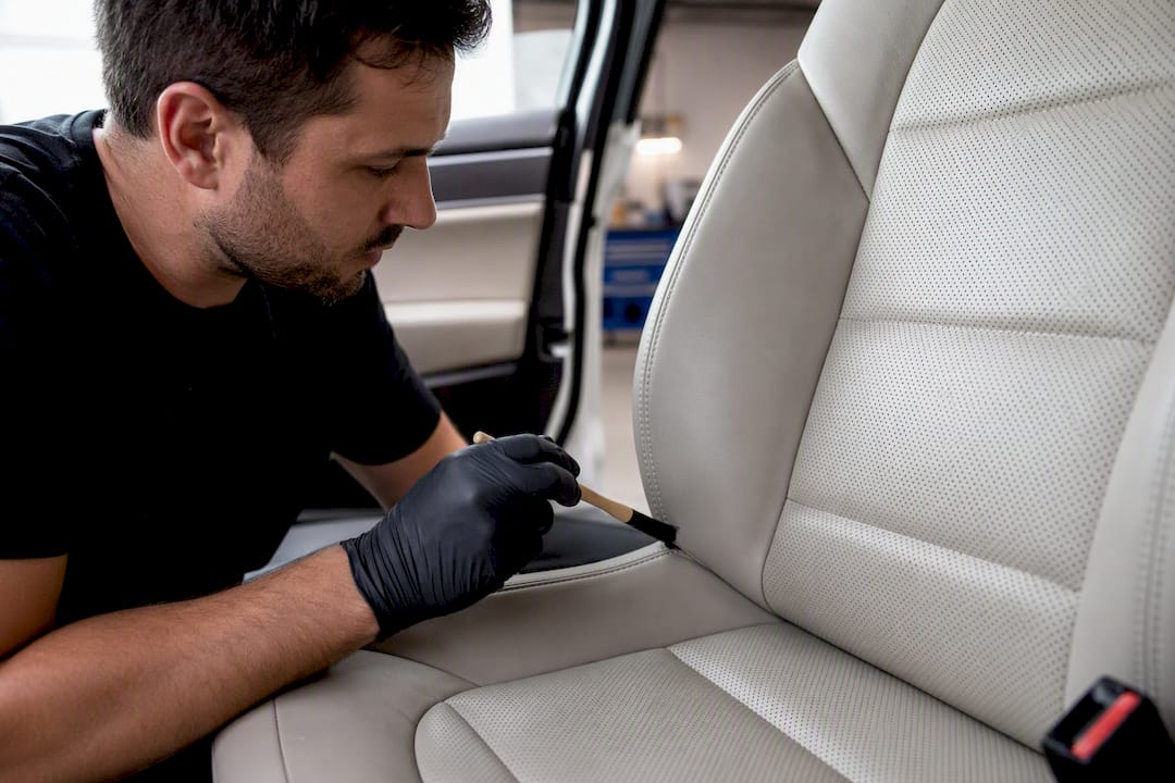 Detailer cleaning seams of leather seat