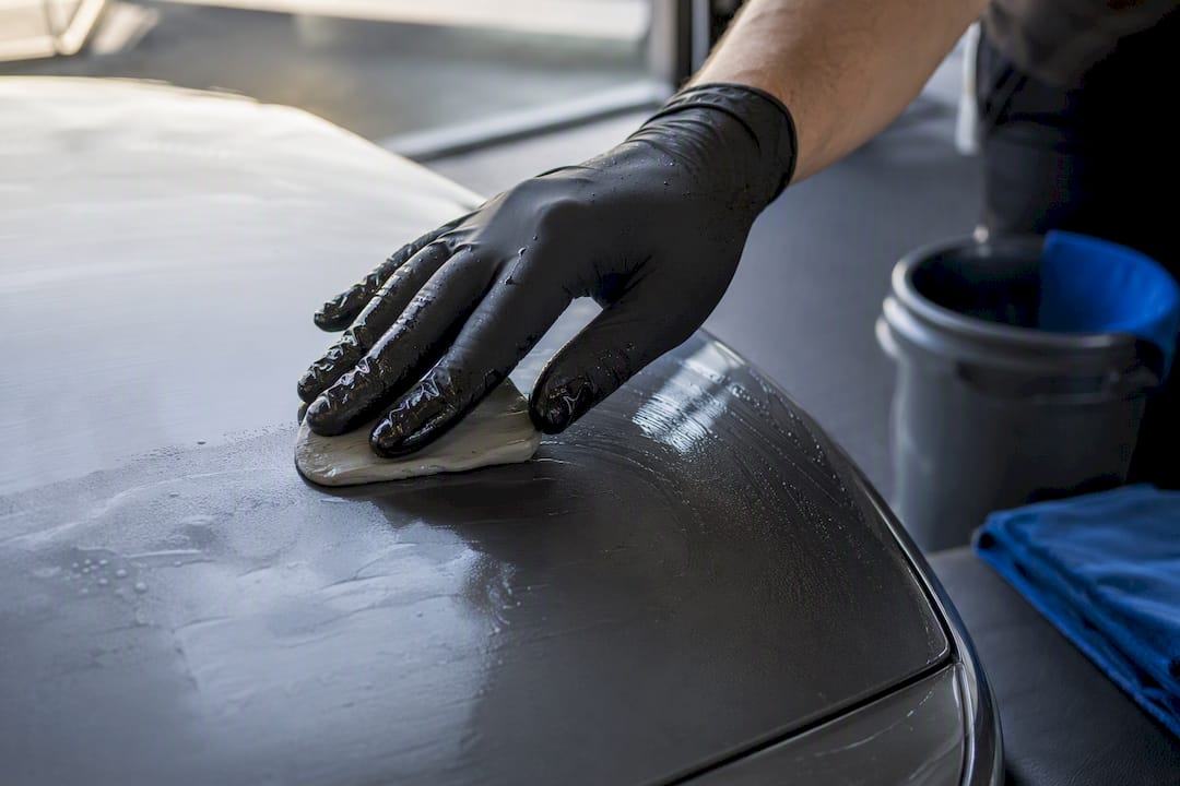 Detailer using clay bar on vehicle paint