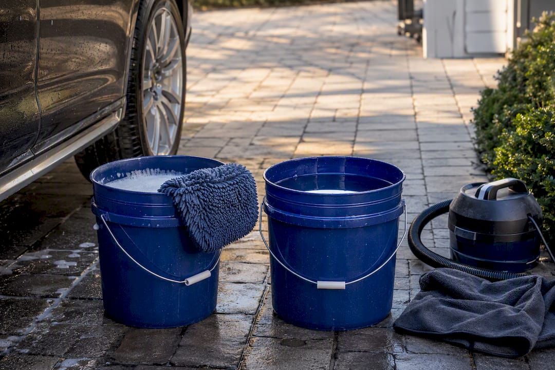 Two-bucket wash setup beside vehicle