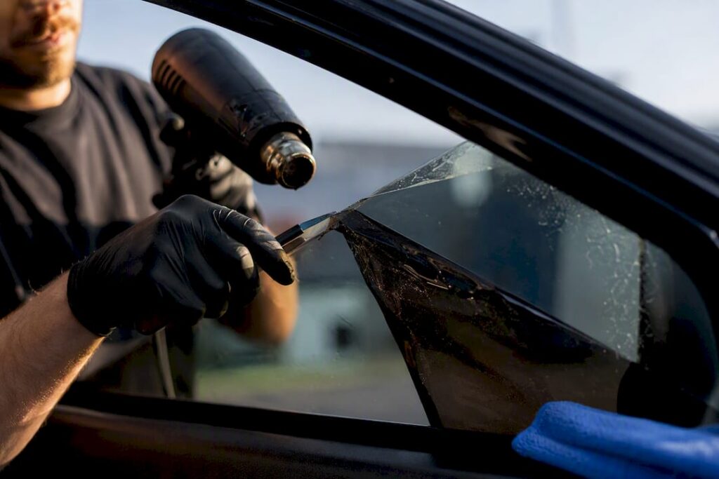 Technician peeling tint film from vehicle glass